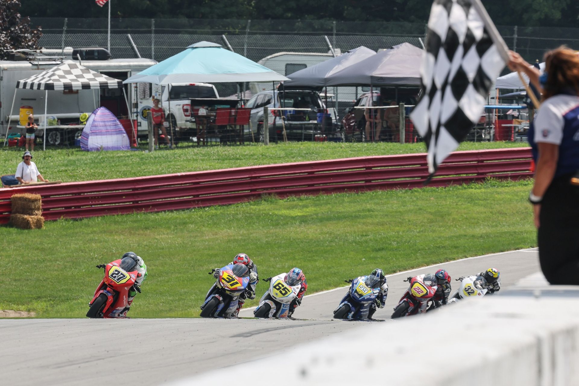 A pack of six Talent Cup racers head to the finish line on the final lap with Alessandro Di Mario (27) winning his fourth race of the season by just .050 of a second over Hank Vossberg (31). Bodie Paige (65), Sam Drane (59), Ella Dreher (22), and Carson King give chase. Photo by Brian J. Nelson