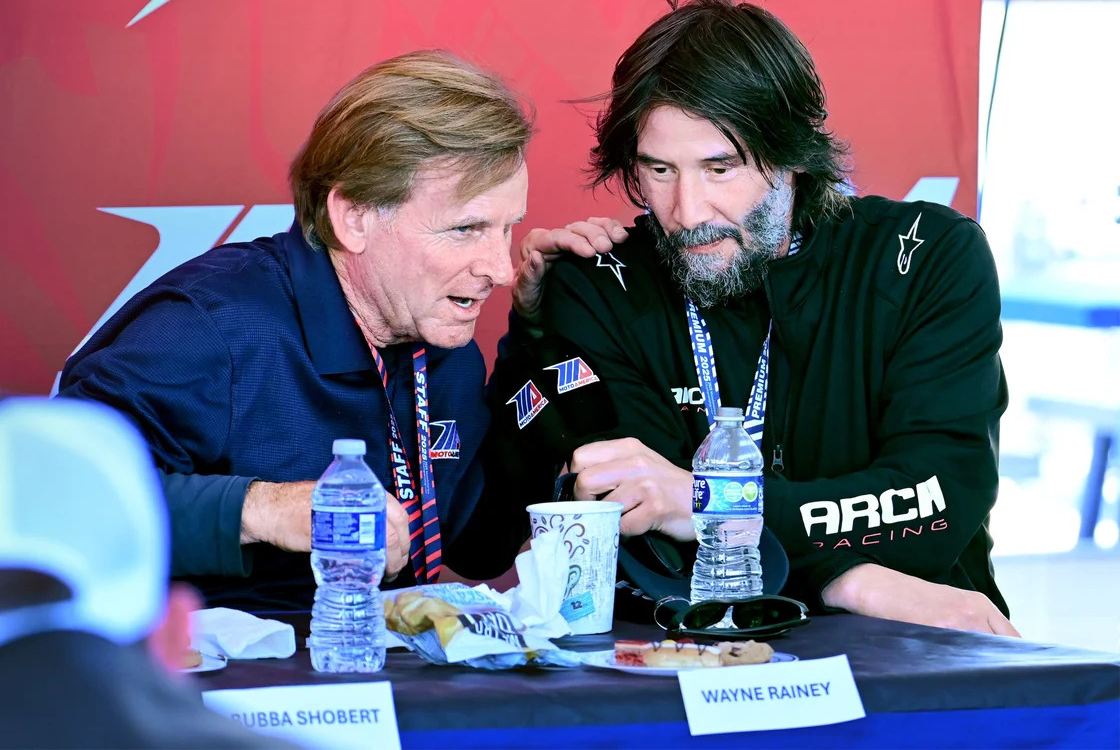V10 Entertainment, the producer of the docuseries featuring Keanu Reeves’ ARCH Racing team, has secured global distribution rights to MotoAmerica’s live racing. MotoAmerica President Wayne Rainey is pictured in discussion with Reeves. Photo courtesy MotoAmerica.